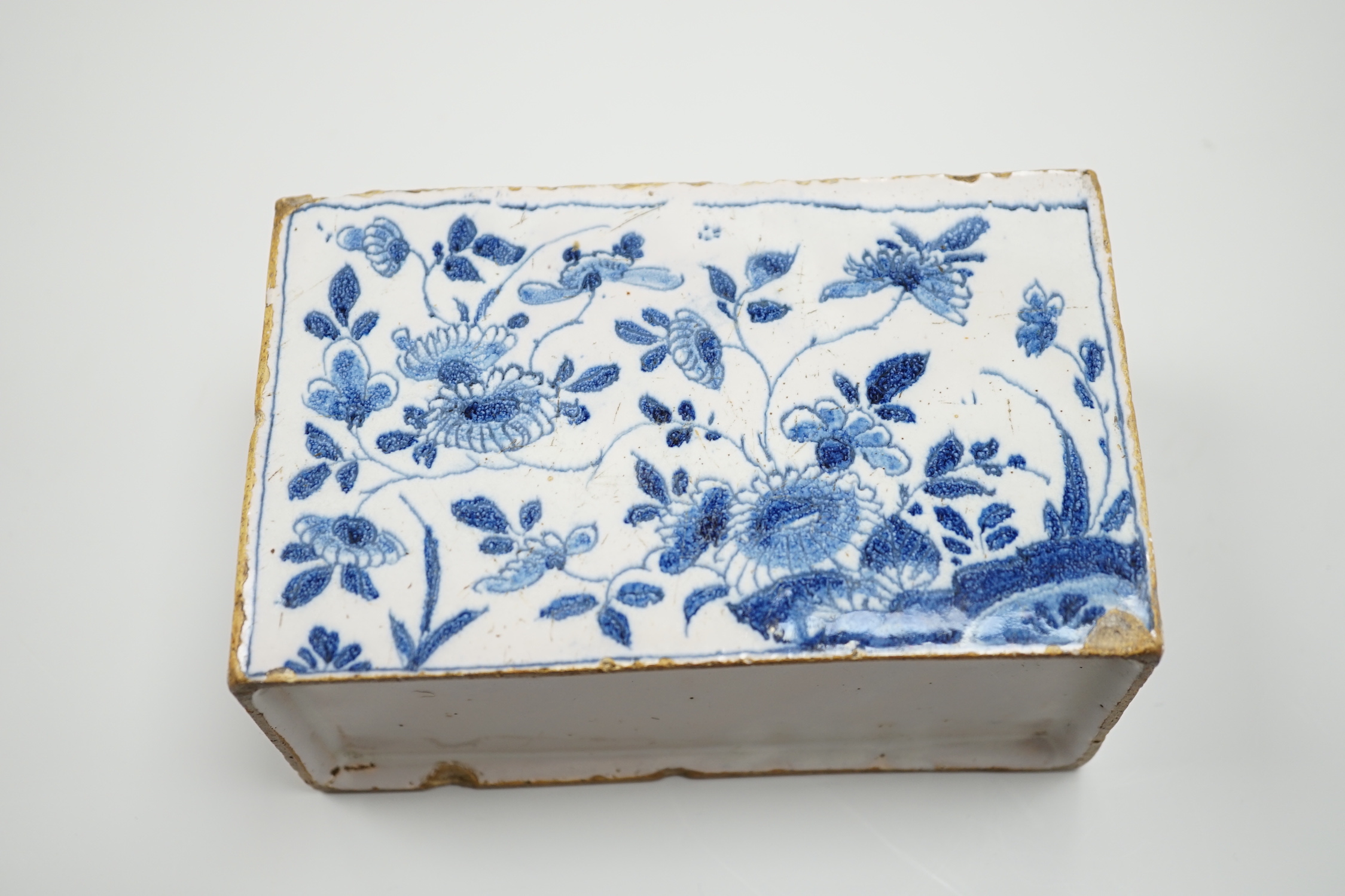 A mid 18th century English delftware flower brick, probably Lambeth, painted in underglaze blue with stylised chrysanthemums, 15cm wide